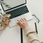 Free An overhead view of a person working on a laptop in a minimalist home office setting. Stock Photo